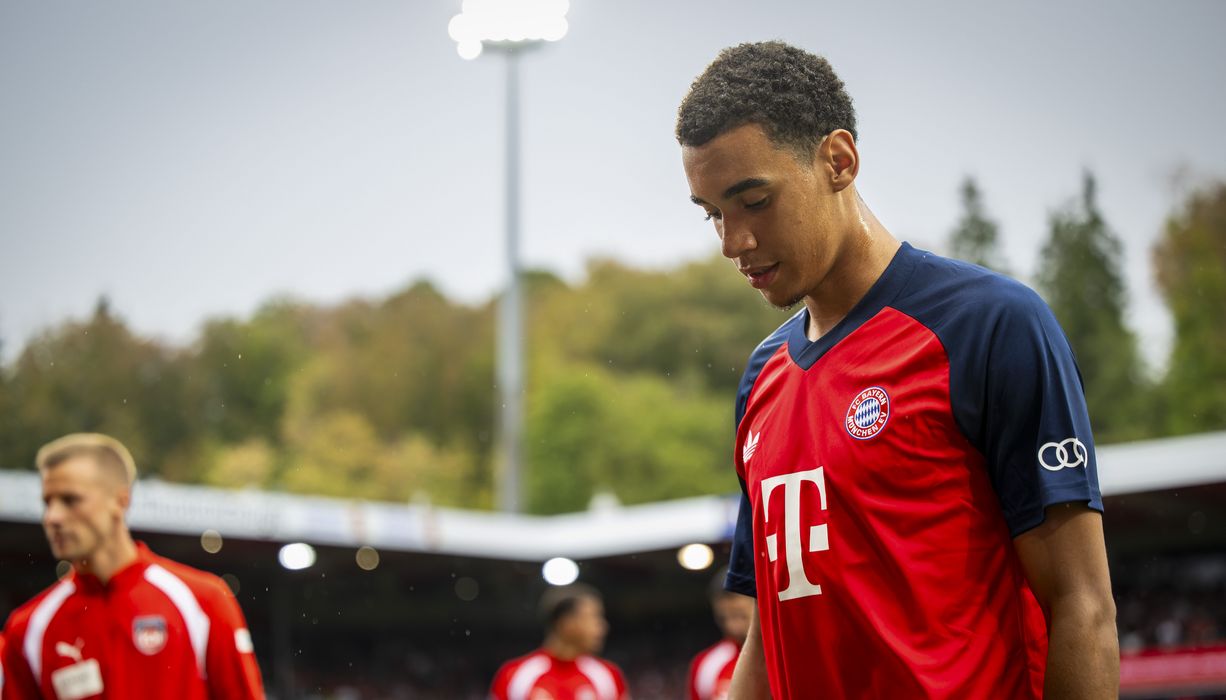 Fußballer Jamal Musiala läuft über den Platz und guckt nachdenklich.