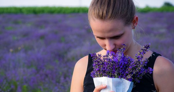 Frau riecht an Blumen.