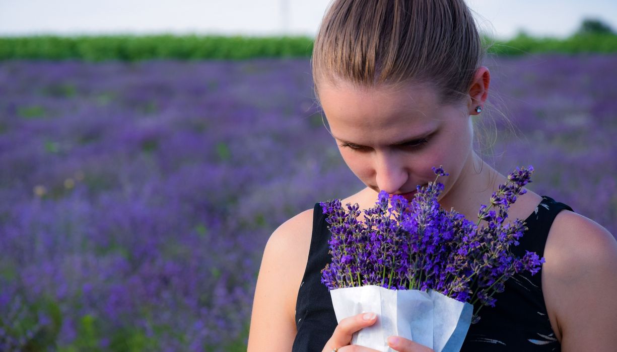 Frau riecht an Blumen.