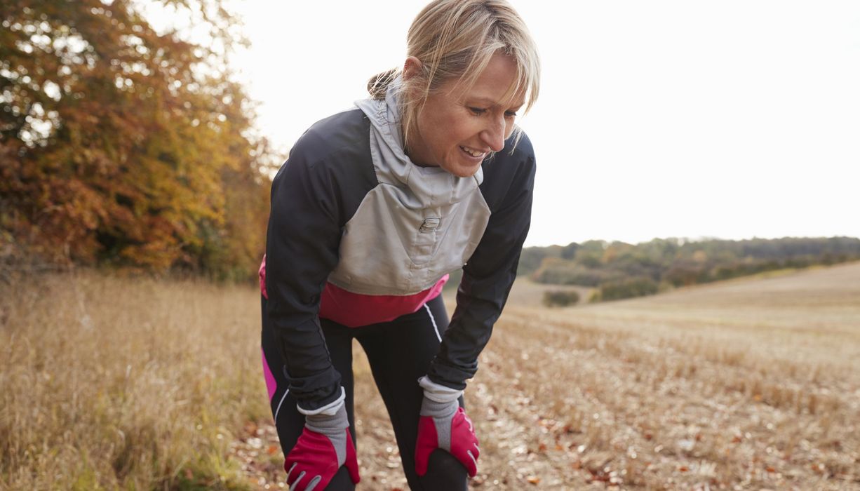 Frau in Joggingkleidung, macht eine Verschnaufpause im Feld.