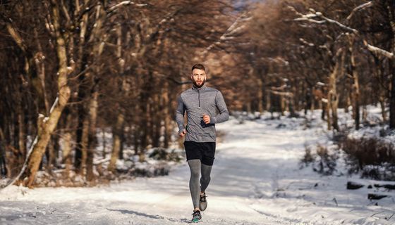 Ein Mann joggt im Winter in einem Park oder Wald