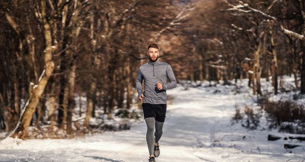Ein Mann joggt im Winter in einem Park oder Wald