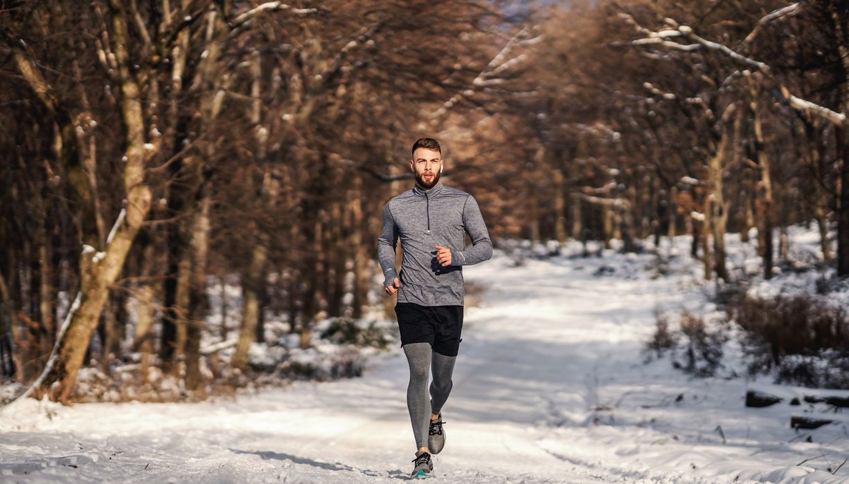Ein Mann joggt im Winter in einem Park oder Wald