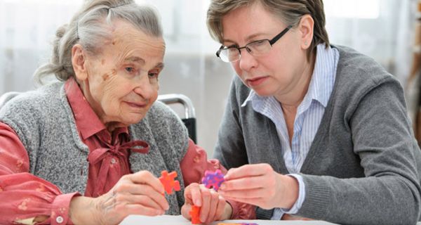Alte Frau (ca. 80) beim Puzzeln mit Frau in den 40ern