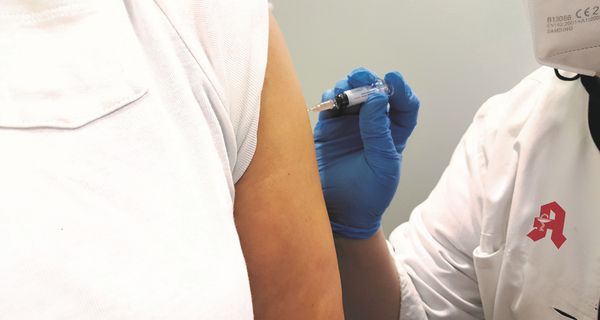 Apotheker impft Patienten gegen Grippe.