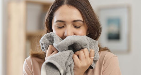 Frau riecht an einem Handtuch.