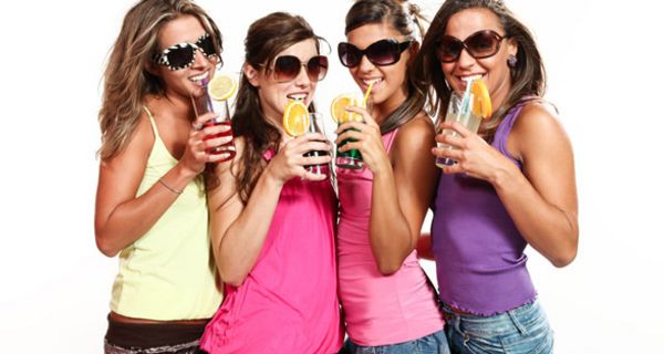 Vier Teenager-Mädchen mit Sonnenbrillen und alkoholischen Mixgetränken