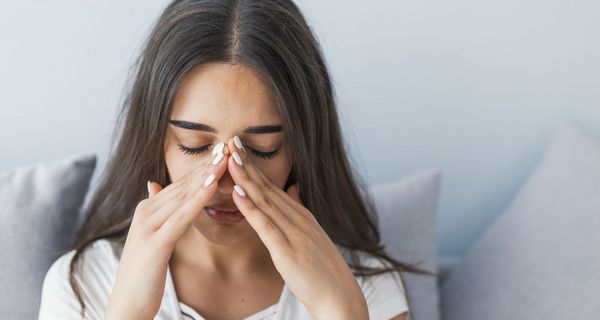 Erkältete Frau hält sich die Nase.