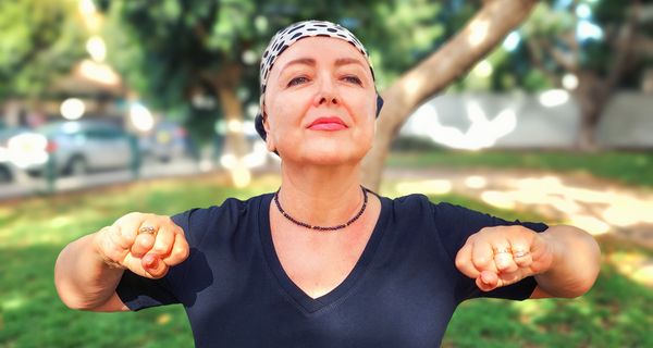 Frau mit Kopftuch hat die Arme angehoben im Park