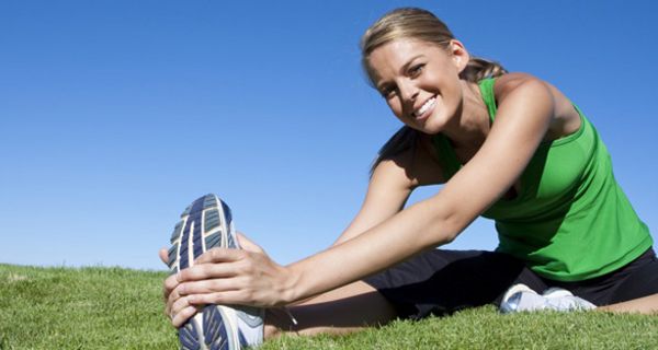 Sportliche junge Frau dehnt die Beinmuskulatur.