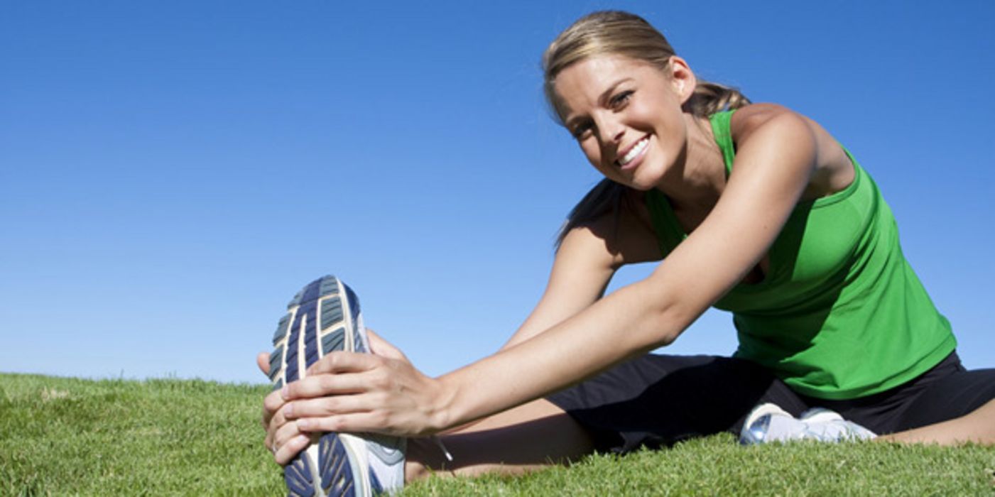 Sportliche junge Frau dehnt die Beinmuskulatur.