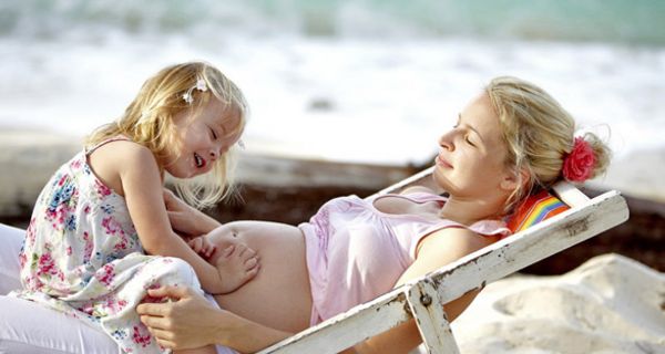 Schwangere mit kleinem Kind auf einer Strandliege