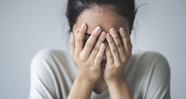 Frau, hält sich die Hände vor das Gesicht.