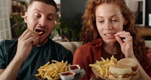 Ein Paar isst Pommes mit Burgern und Dips.