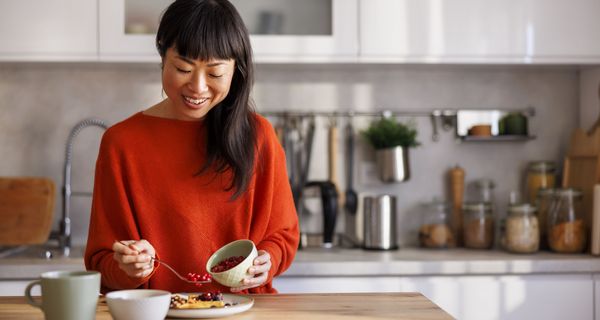 Frau, bereitet sich Pfannkuchen mit Beeren vor.