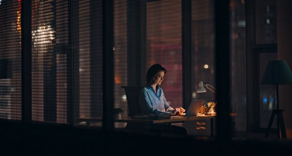 Frau, sitzt abends im Büro und arbeitet.