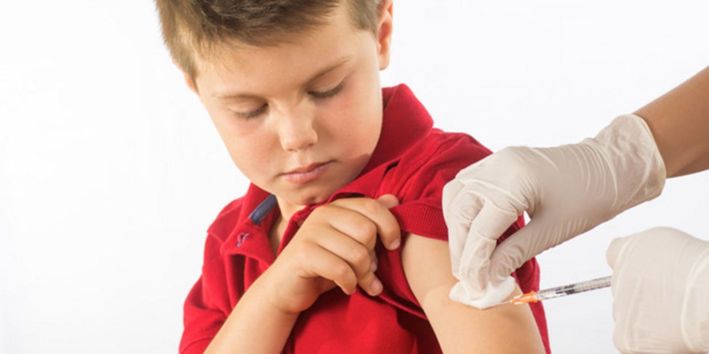 Junge im roten Poloshirt bekommt eine Grippeimpfung