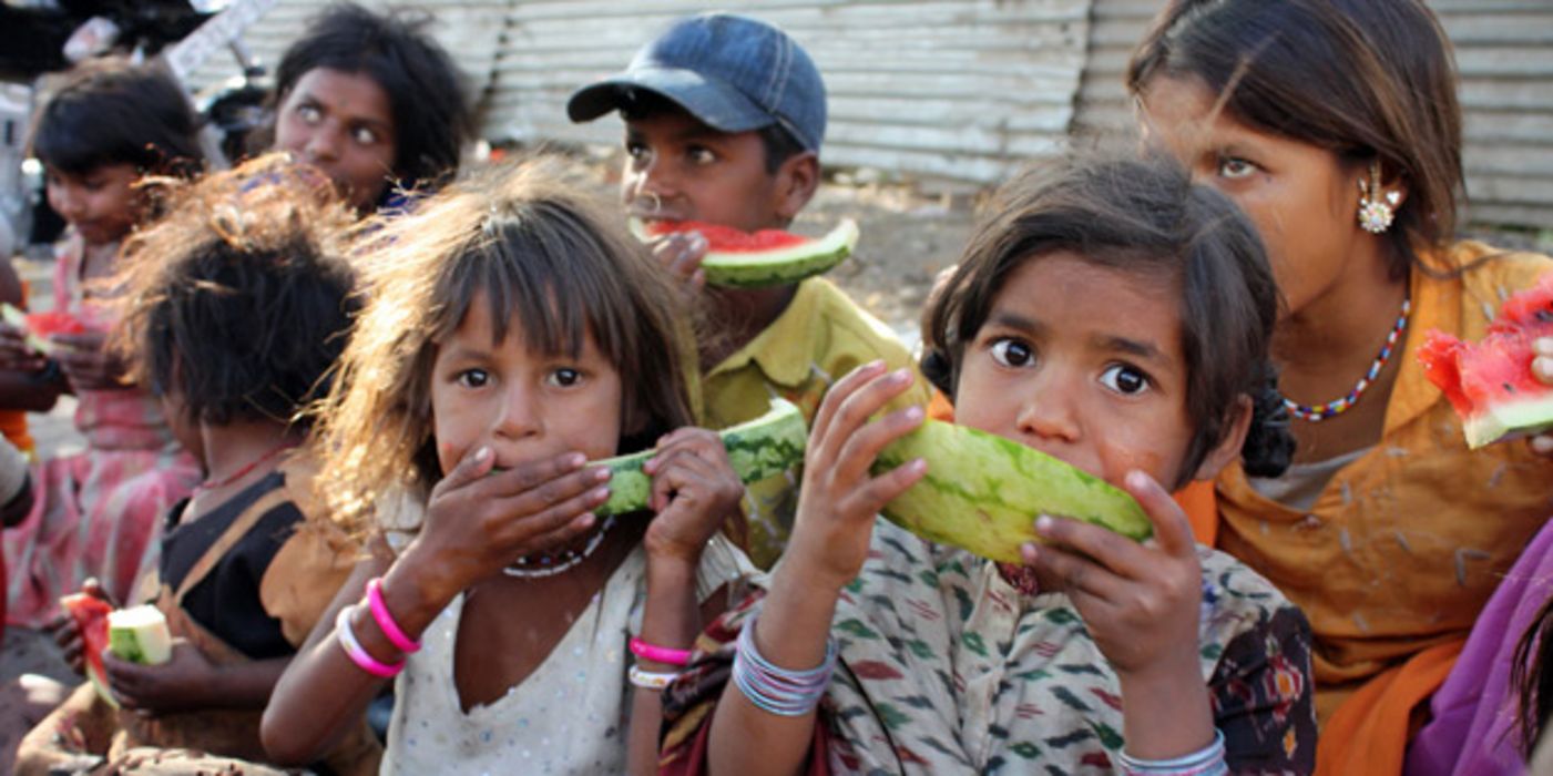 Gruppe indischer Kinder, die Melonenschnitze essen und in die Kamera schauen