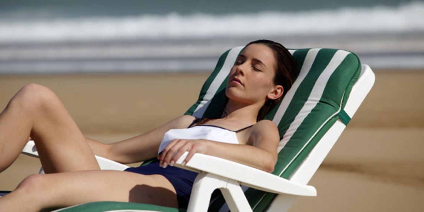 Junge Frau im Badeanzug mit geschlossenen Augen sonnt sich 