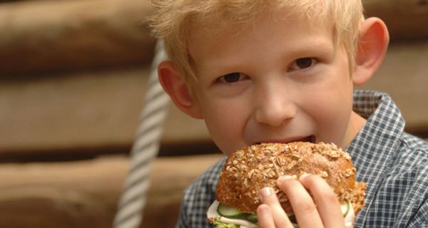 Kleiner Junge isst ein Vollkornbrötchen