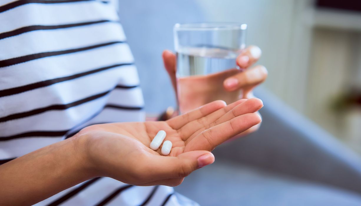 Frau, hält zwei Tabletten in der Hand.