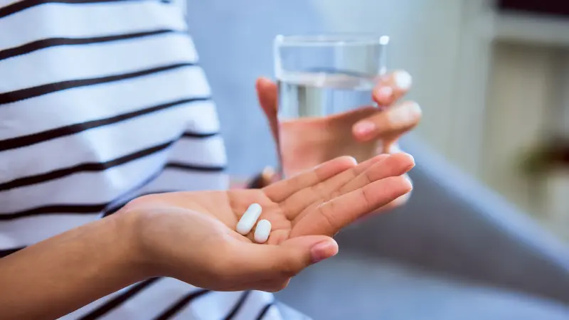 Frau, hält zwei Tabletten in der Hand.