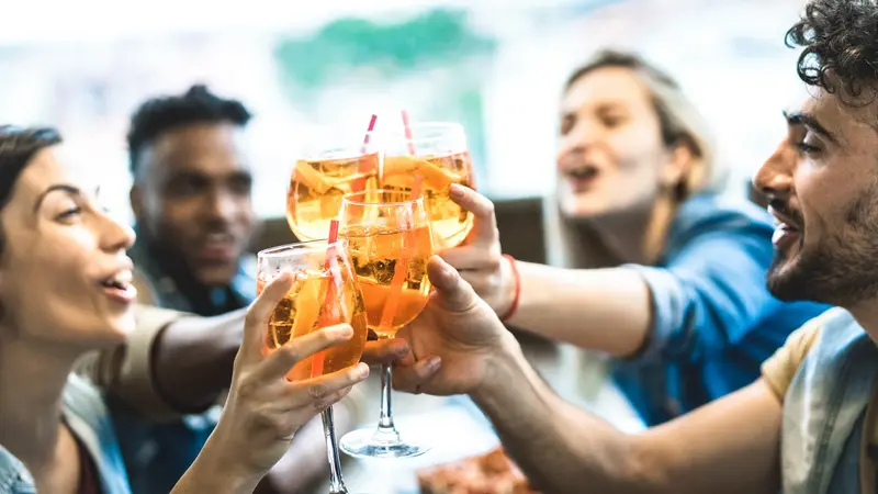 Junge Leute stoßen mit Wein an.