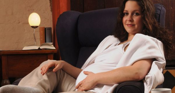 Schwangere sitzt im Sessel.
