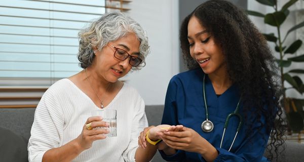 Eine Medizinerin gibt einer Patientin Medikamente sowie Erklärungen dazu. 