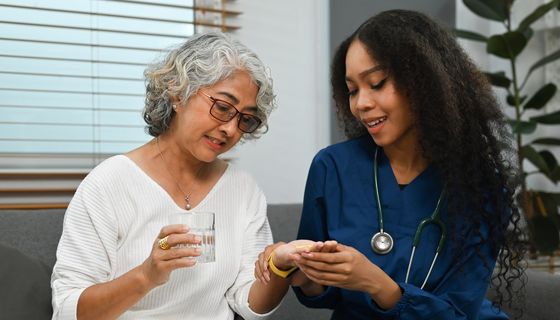 Eine Medizinerin gibt einer Patientin Medikamente sowie Erklärungen dazu. 