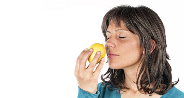 Frau riecht an einer Zitrone, Augen sind geschlossen
