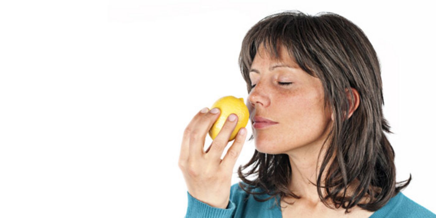 Frau riecht an einer Zitrone, Augen sind geschlossen