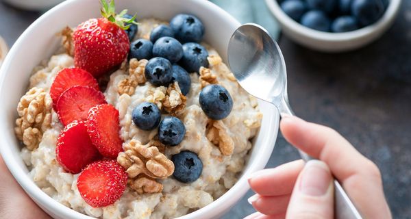 Schüssel mit Haferbrei und Erdbeeren, Walnüssen und Blaubeeren