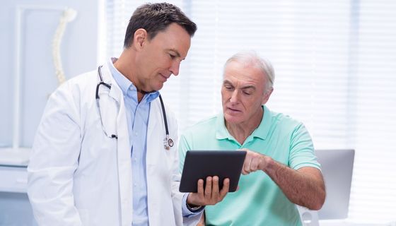 Arzt zeigt Patienten etwas auf dem Tablet.