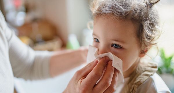 Einem etwa ein Jahre altem Kind wird die Nase geputzt.