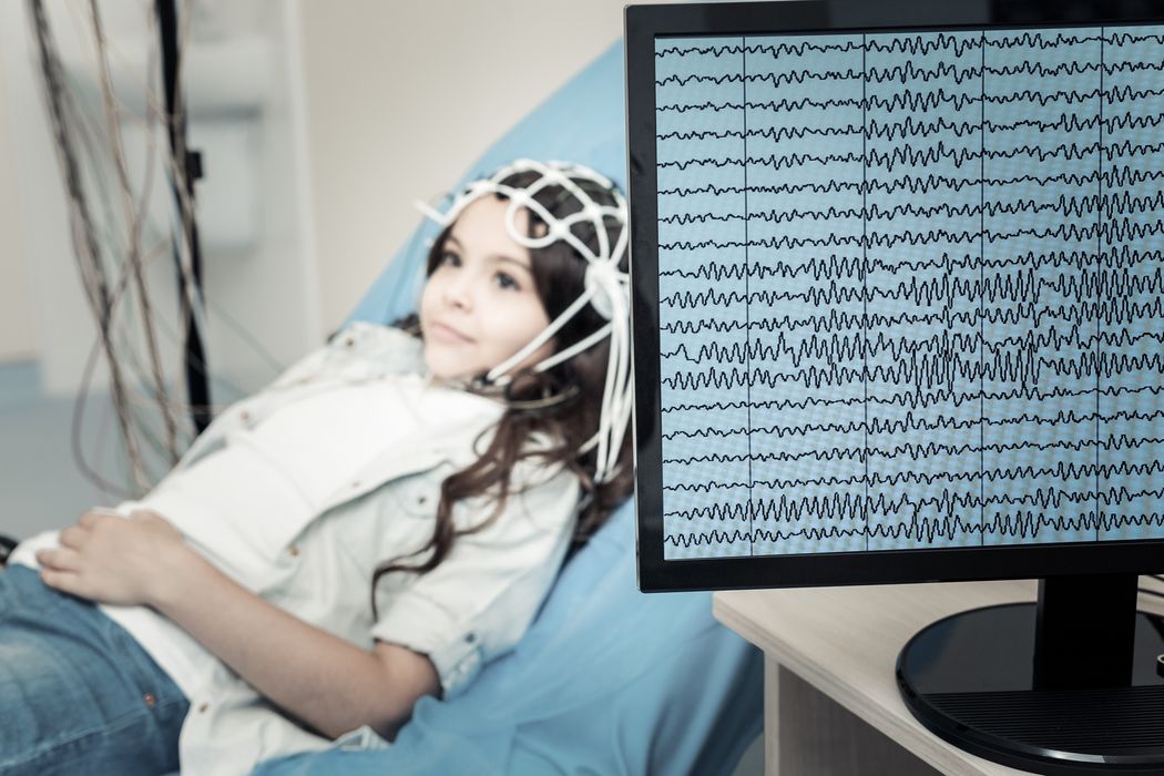 Ein Kind liegt angeschlossen an ein EEG auf einer liege im Krankenhaus.