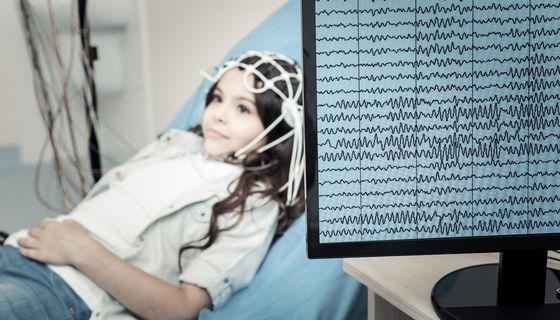 Ein Kind liegt angeschlossen an ein EEG auf einer liege im Krankenhaus.