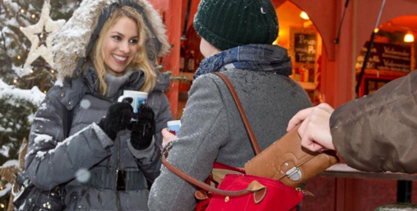 Taschendieb auf dem Weihnachtsmarkt zieht Geldbörse aus der Unmhängetasche einer Frau