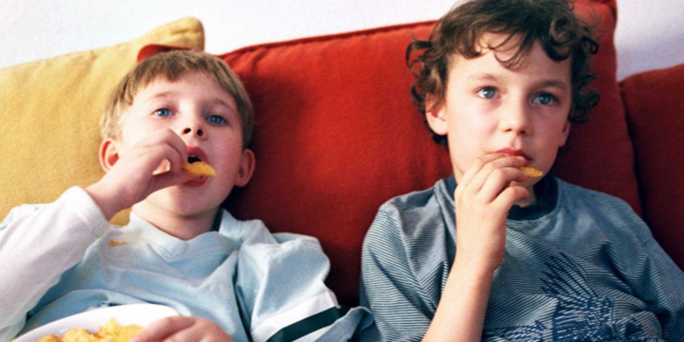 Zwei Kinder schauen TV und futtern Chips