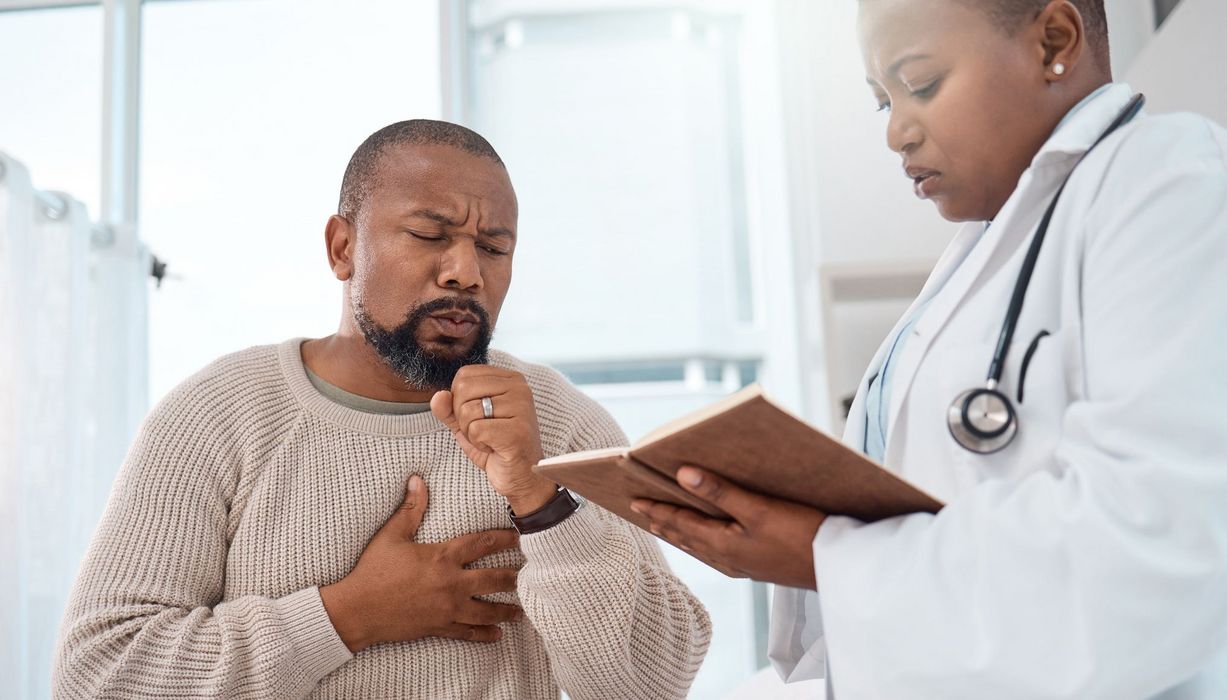 Mann hustet bei einer Ärztin