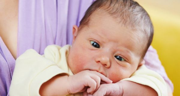 Mutter trägt schielendes Baby auf dem Arm