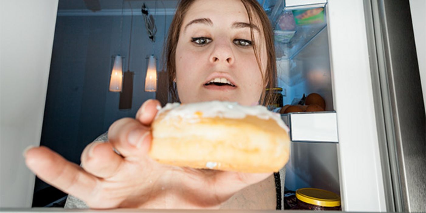 Innen nach außen Foto Kühlschrank mit Frau, die gierig nach einem Donut greift