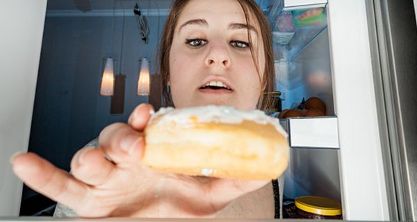 Innen nach außen Foto Kühlschrank mit Frau, die gierig nach einem Donut greift