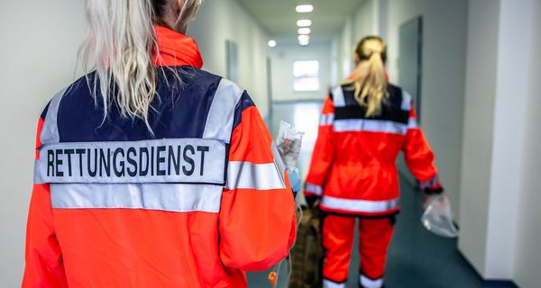 Zwei Frauen vom Rettungsdienst, laufen durch einen Flur.