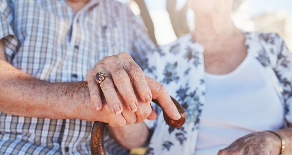 Älterer Mann und Frau, stützen sich auf Gehstock und halten sich an der Hand, Nahaufnahme.