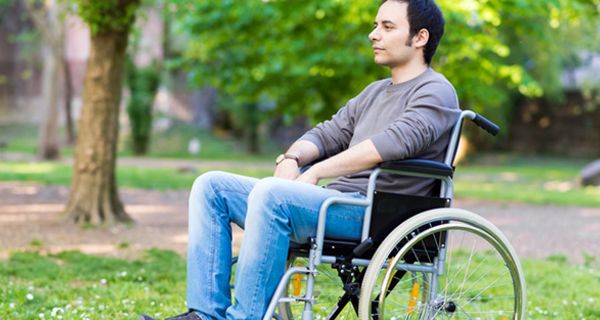 Jüngerer Mann im Rollstuhl in einem Park