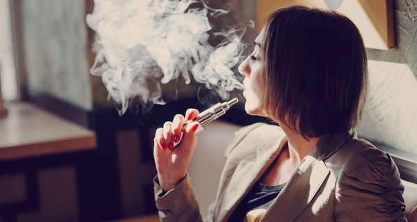 Junge Frau, nutzt eine E-Zigarette.