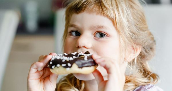 Junges Mädchen, beißt in einen Donut.