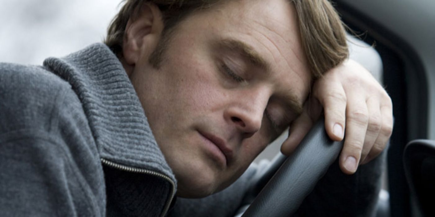 Mann schläft am Steuer eines Autos