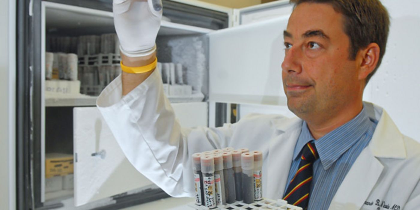 Labormitarbeiter begutachtet ein Röhrchen mit Blutprobe